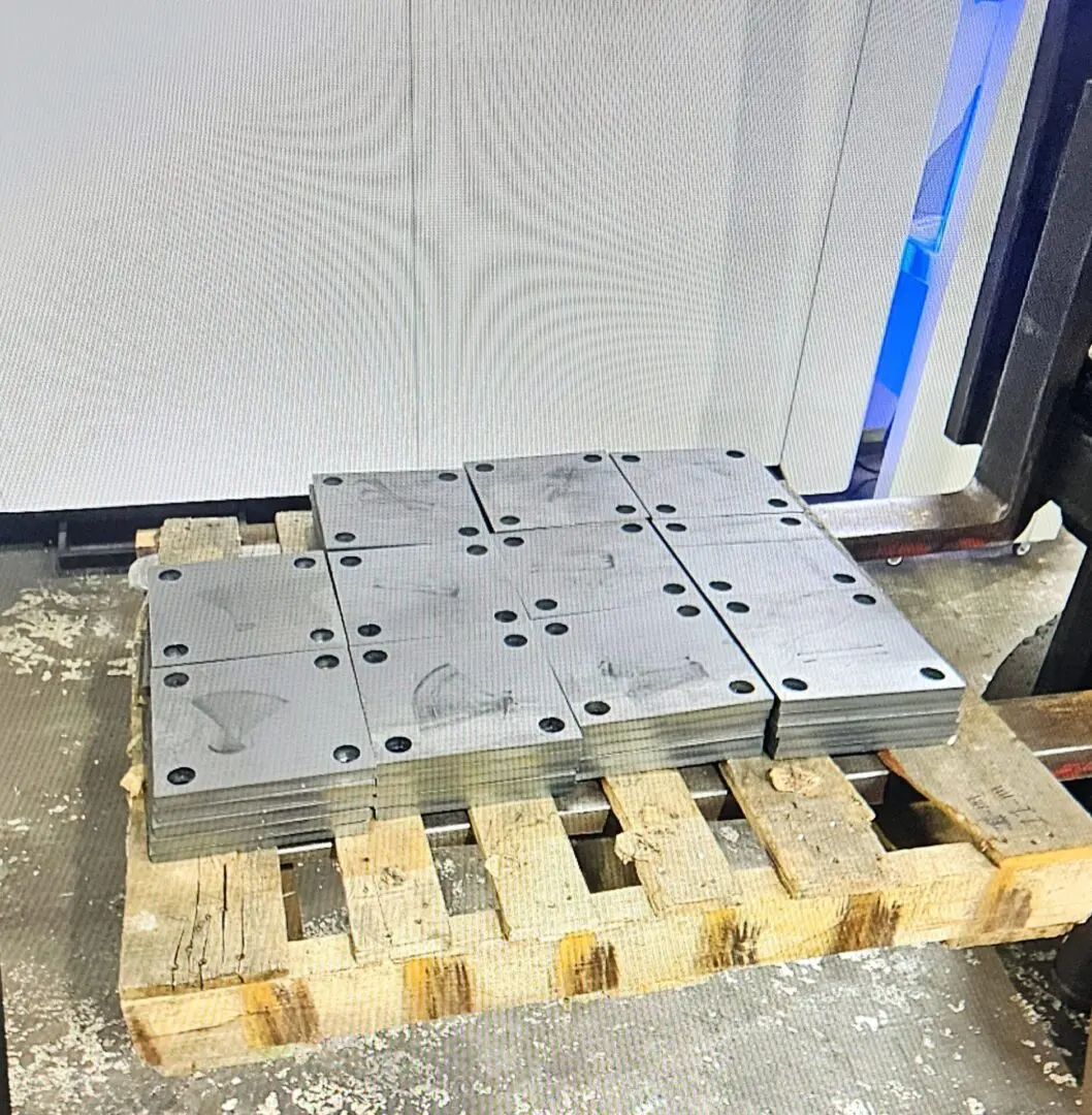 A pallet of metal parts sitting on top of wooden pallets.