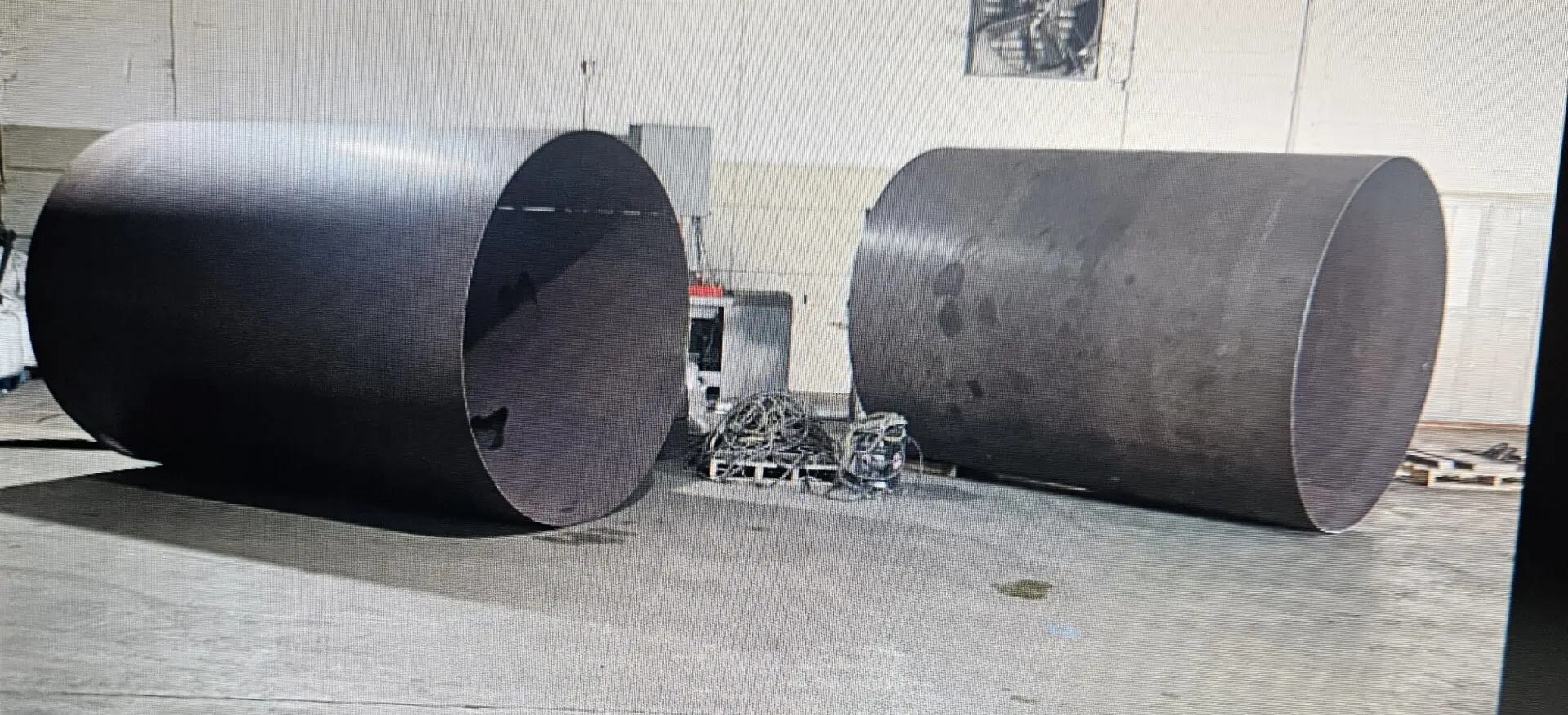 Two large metal pipes are next to a machine.