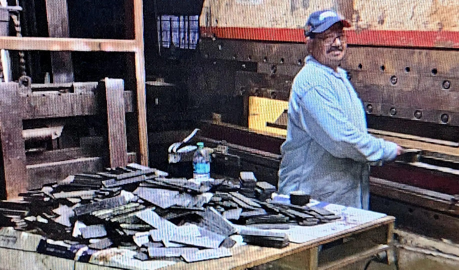 A man standing in front of a table with many pieces of metal.