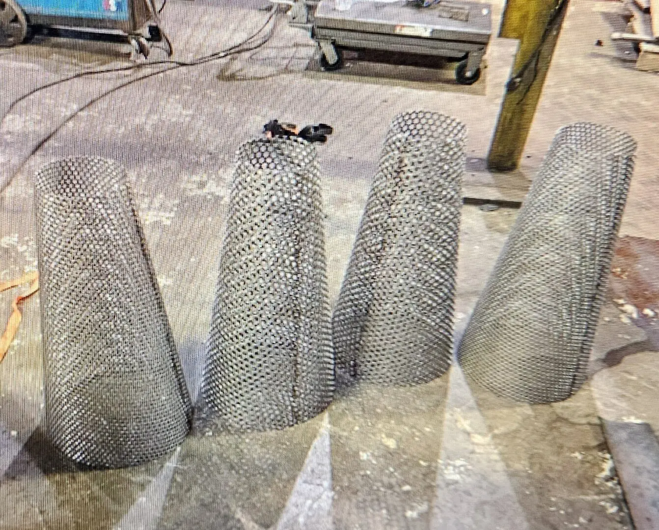 A group of four concrete cones sitting on top of cement.