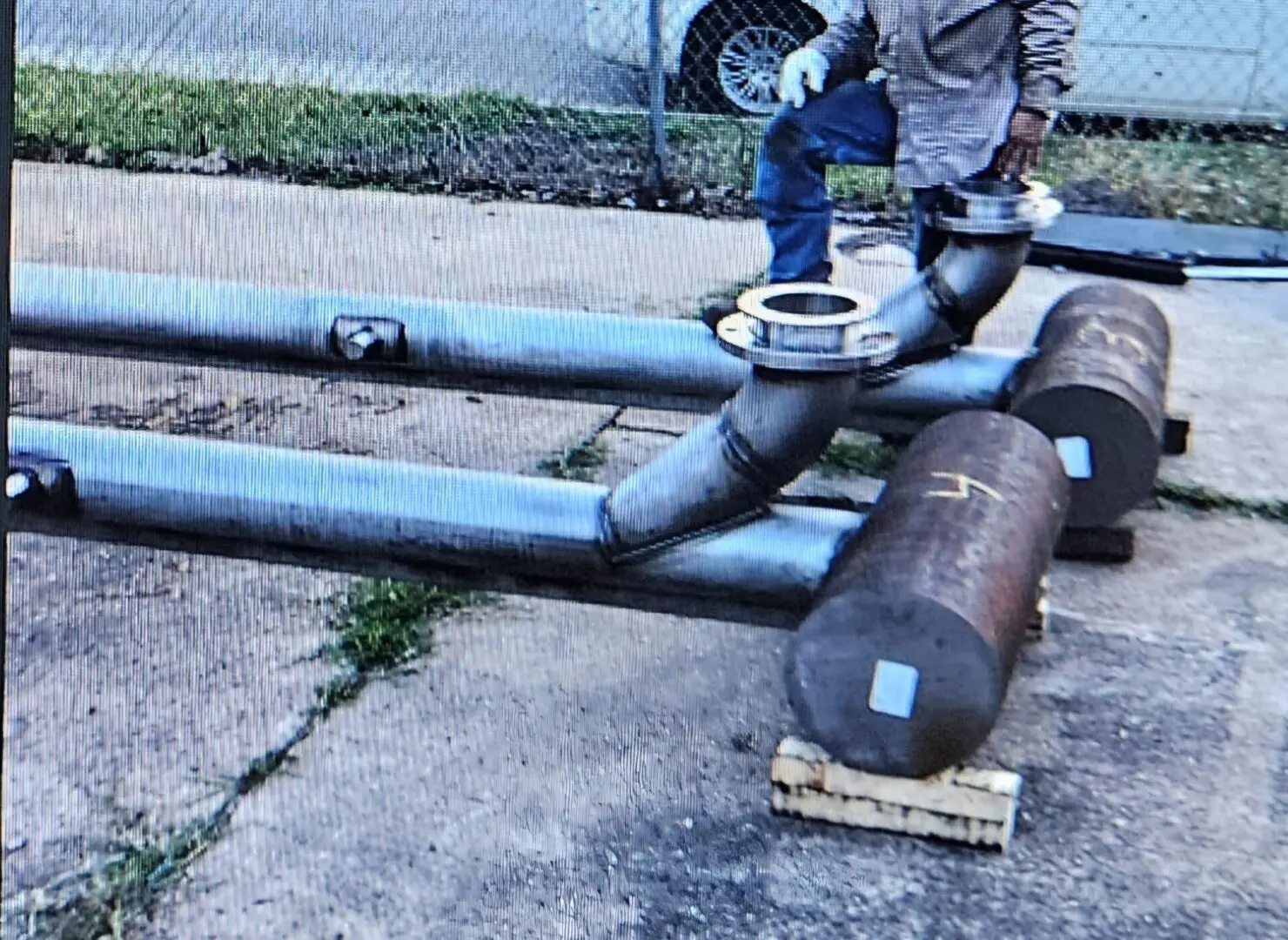 A man standing next to pipes on the ground.