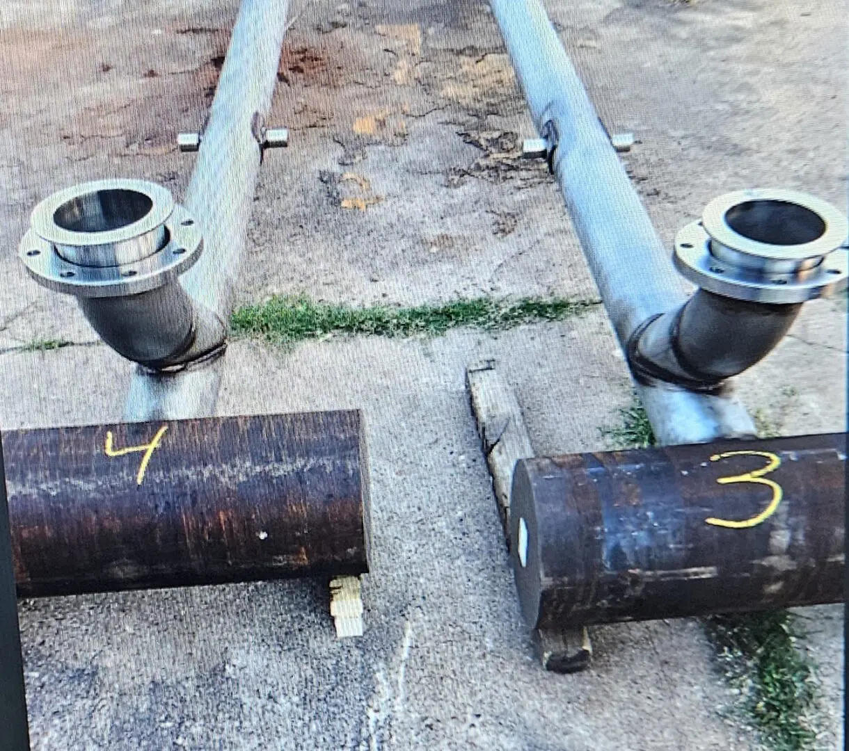 Two pipes that are connected to a pipe laying on the ground.